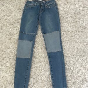 Blue straight jeans with lighter blue patches on the knees